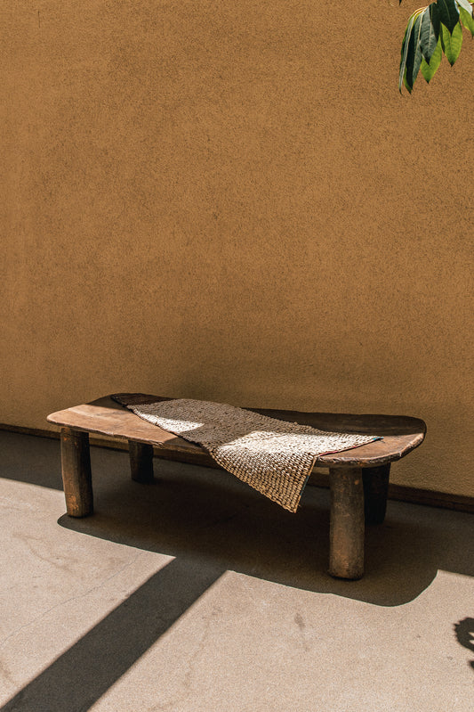Hausa cowrie shell tapestry hanging against a wall, showing the full woven panel