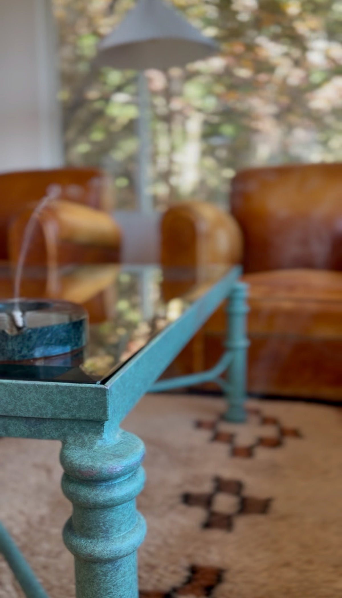 Beveled glass top resting on the verdigris metal base of the coffee table