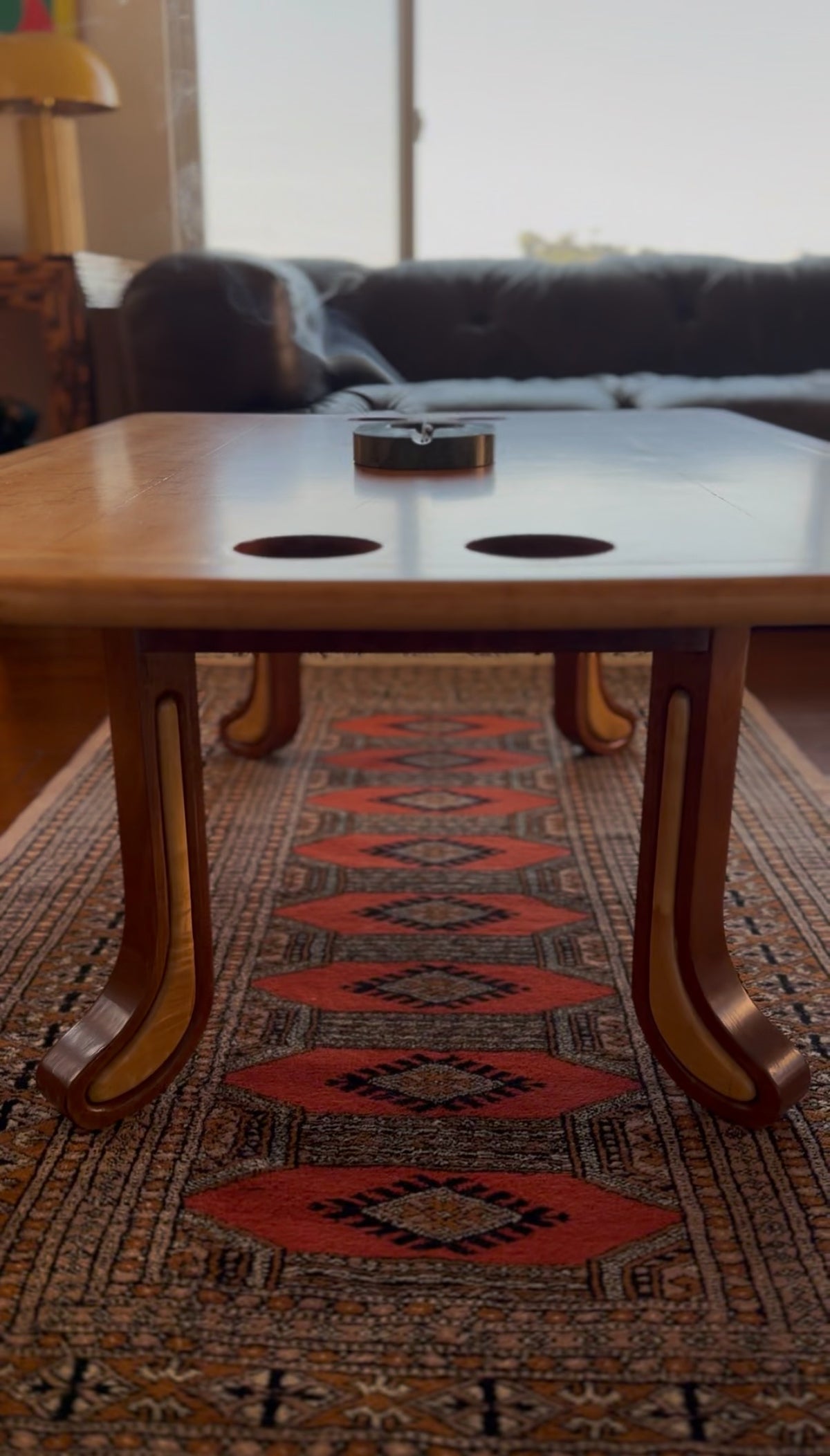 Sculpted studio craft coffee table in two-tone hardwood with carved legs