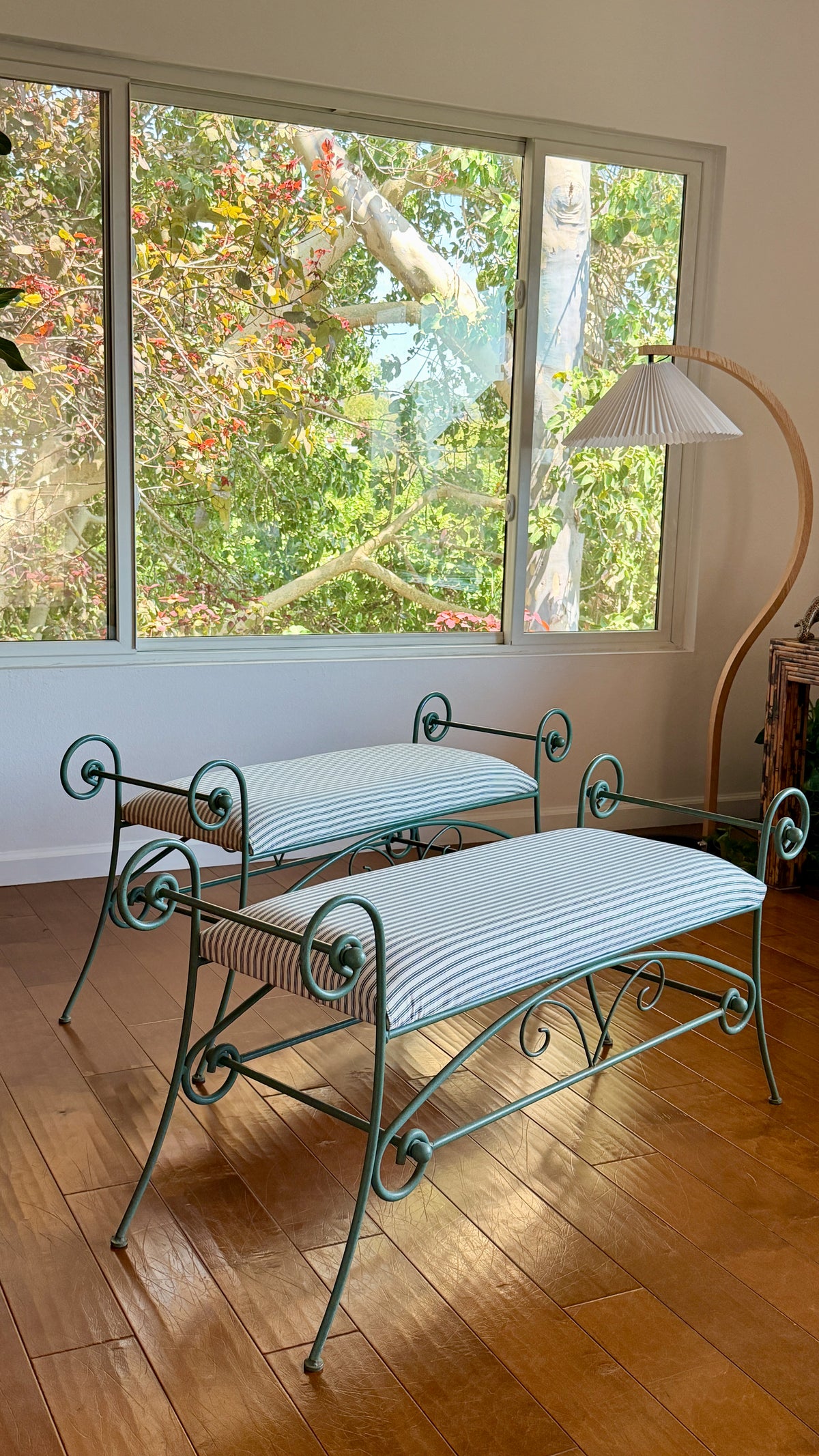 Green scrolled iron bench with rolled arms and ball finials, newly upholstered in ticking stripe