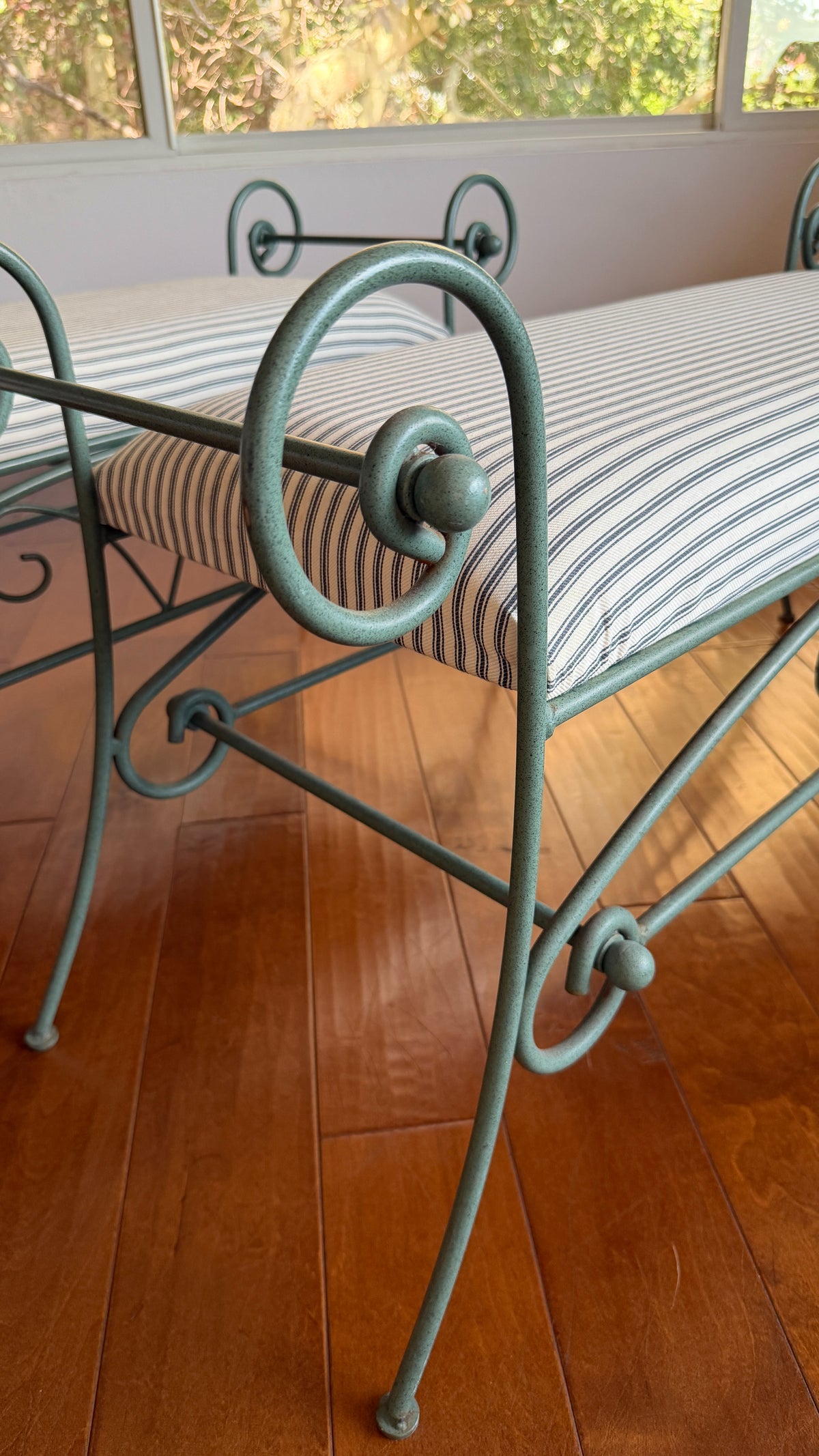 Detail of the rolled arm scroll and ball finial on the green iron window bench