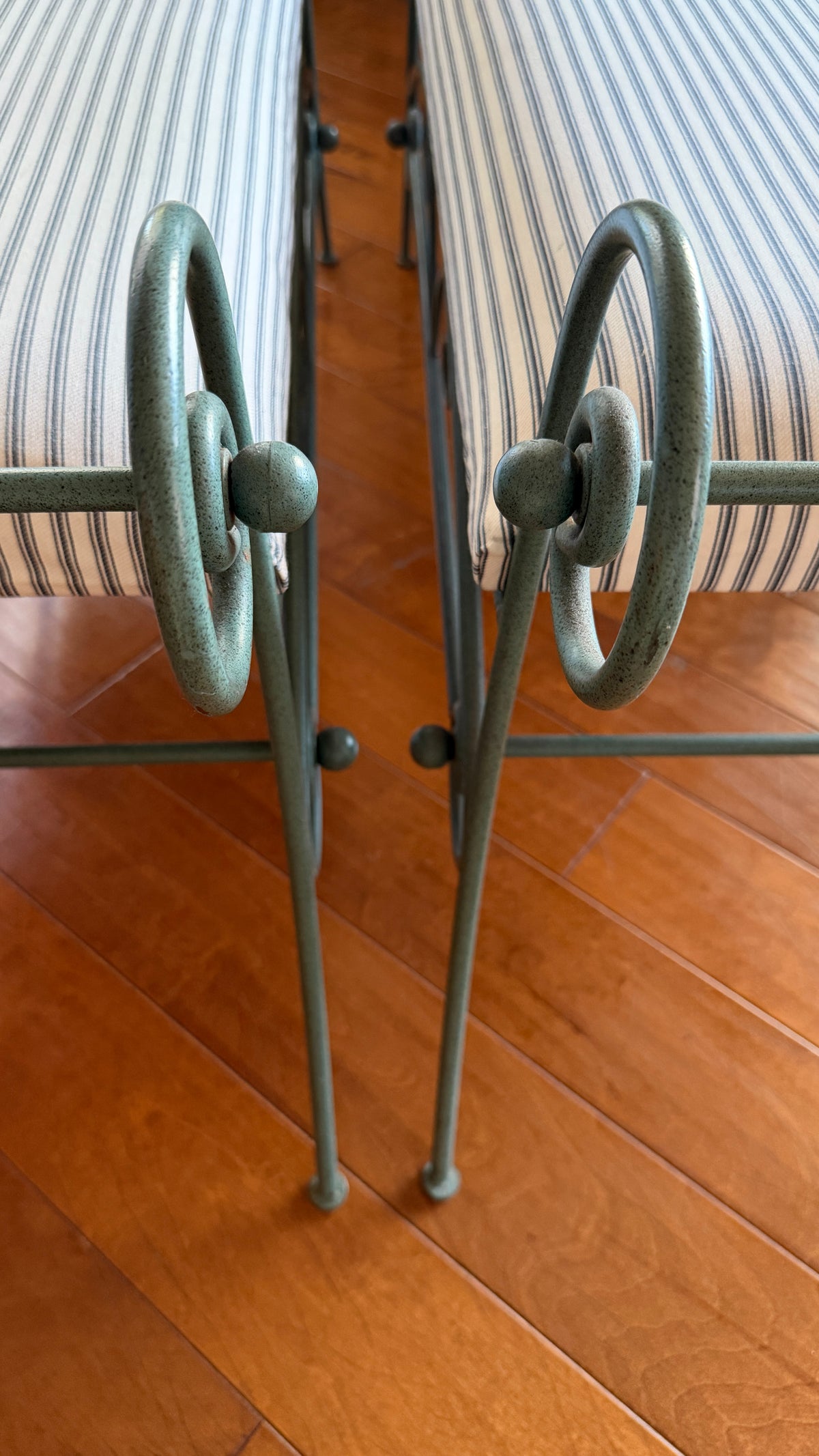 Ball foot detail on the splayed leg of the green scrolled iron bench