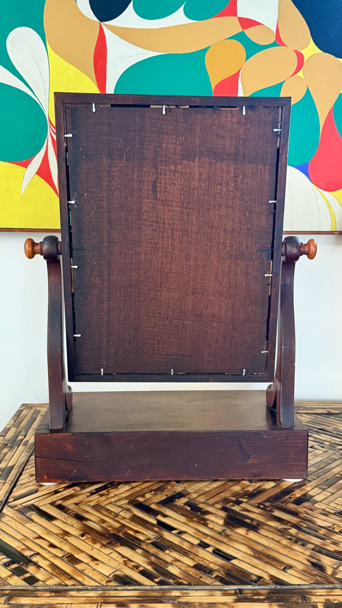 Antique European dressing mirror in flame mahogany, styled on a bamboo surface in natural light