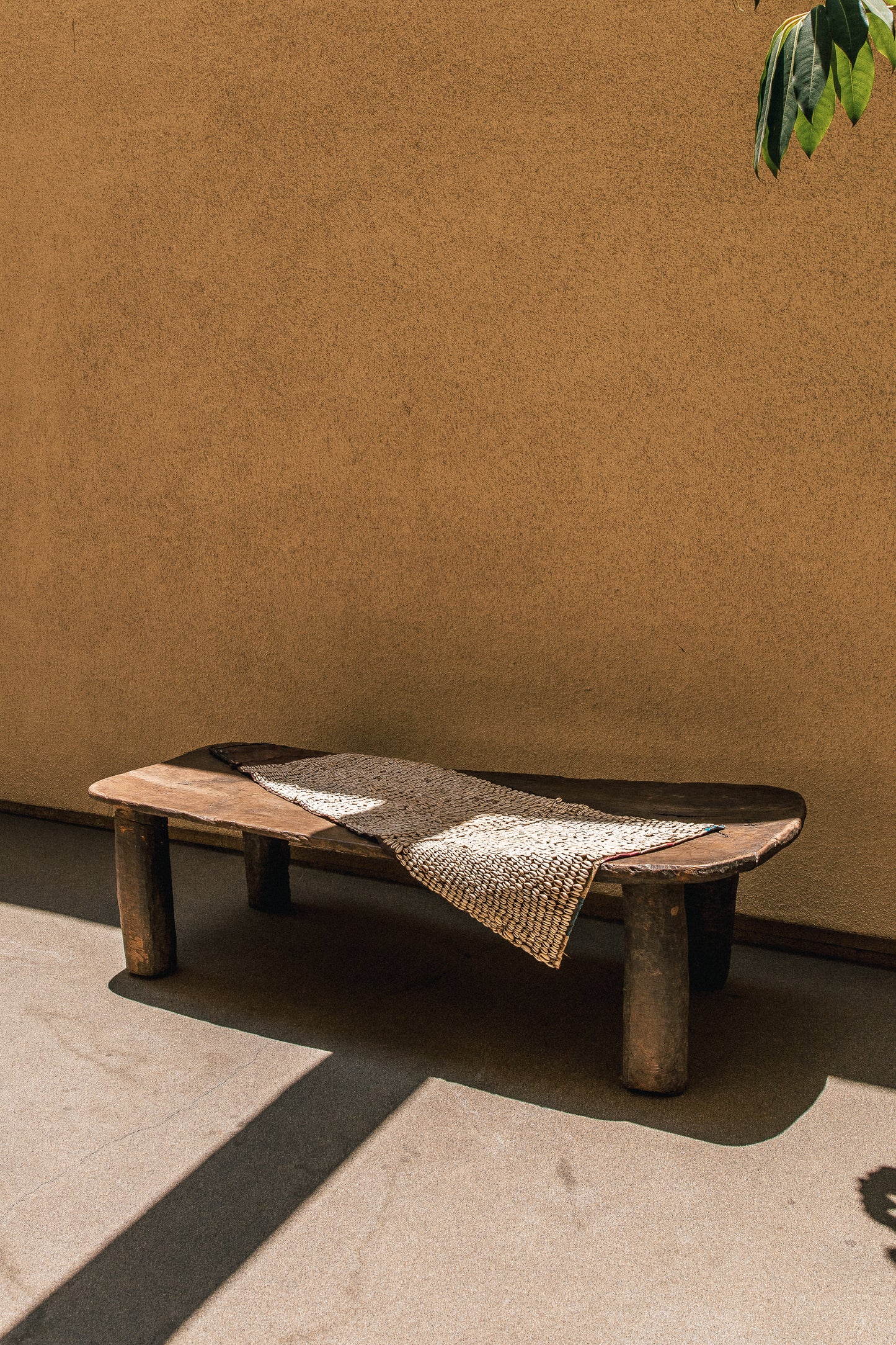 Hausa cowrie shell tapestry hanging against a wall, showing the full woven panel