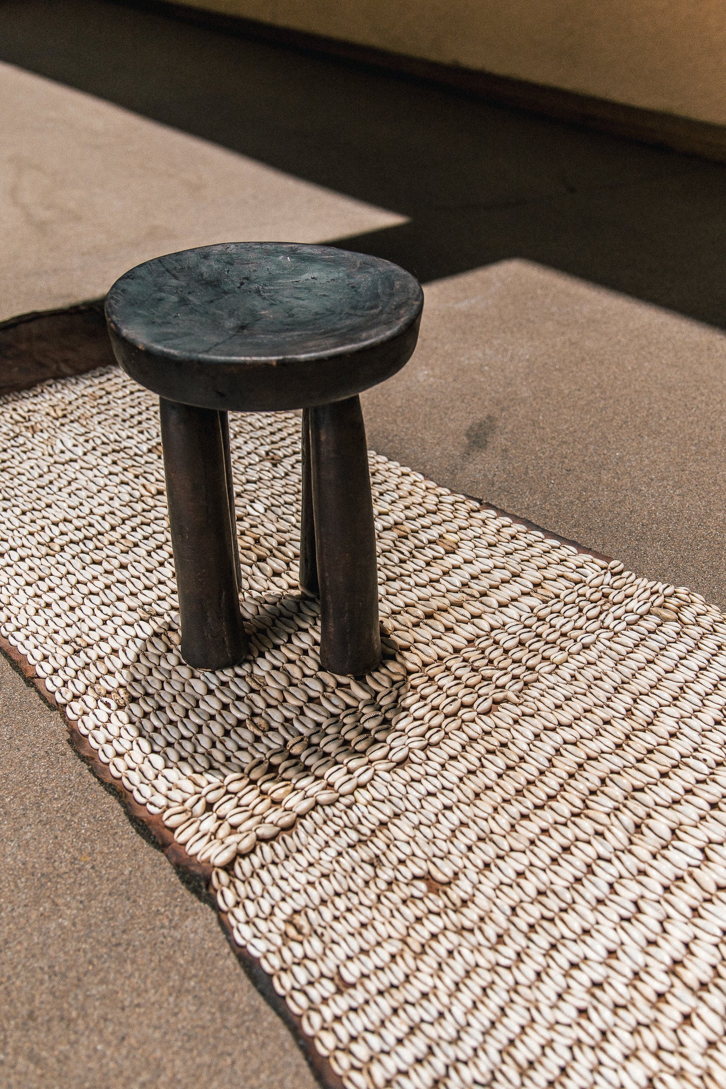 Cowrie shell tapestry photographed in natural light against a neutral wall